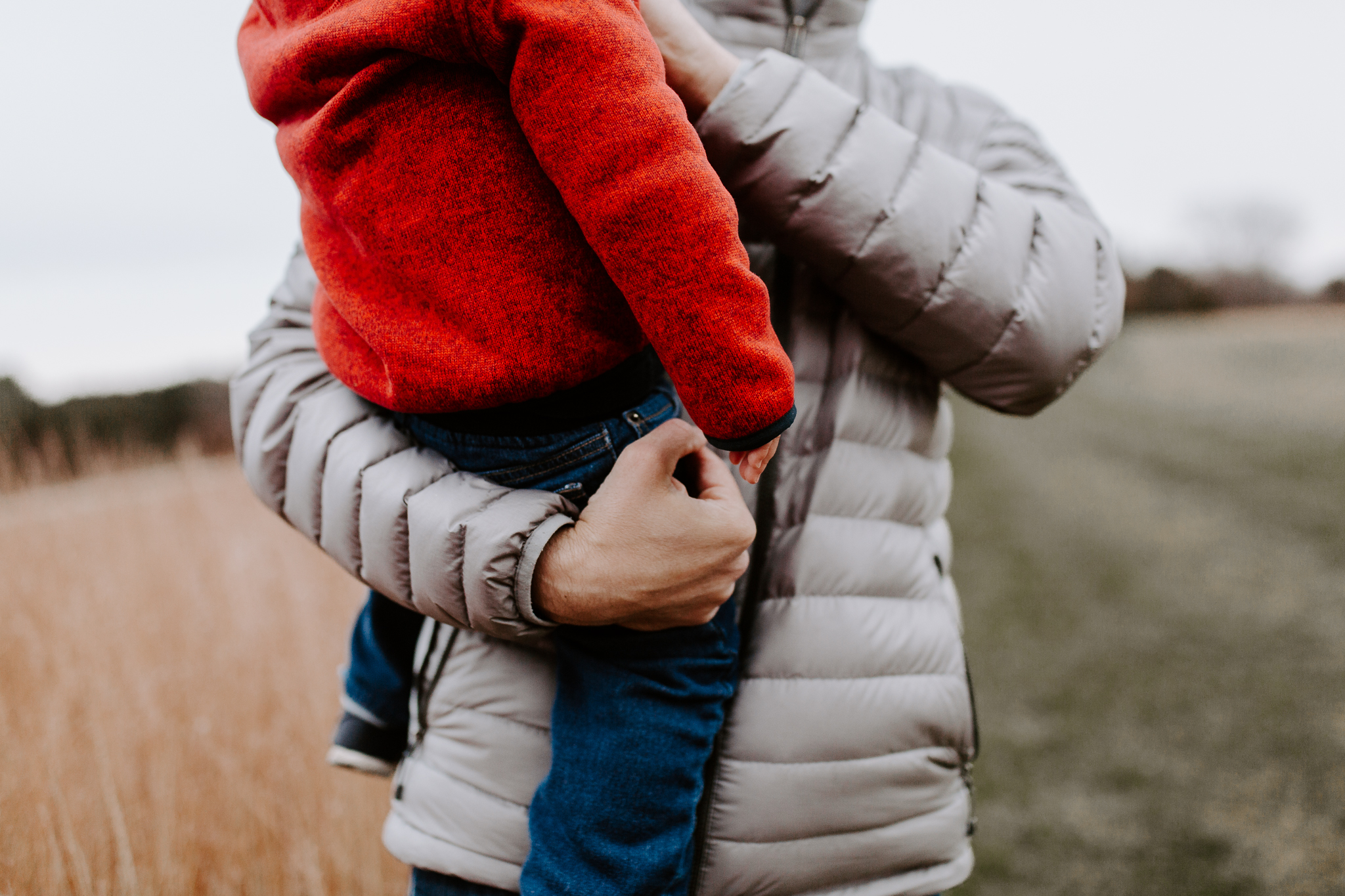 Father in a winter coat holding his young son tightly in the cold.